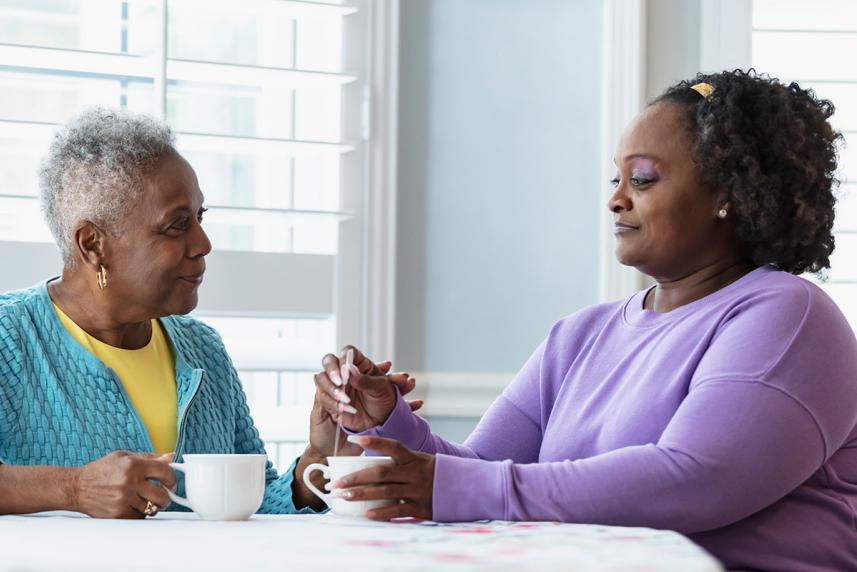 Two women sitting at a table, each holding a coffee mug